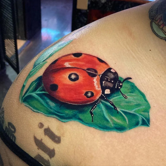 Medium Realism Ladybug on Leaf Tattoo on Women Shoulder by @cheyenne.tattoos