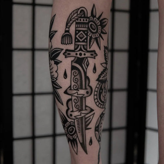 Medium Traditional Dagger and Flowers Tattoo on Men Leg by @yuri.tattoos