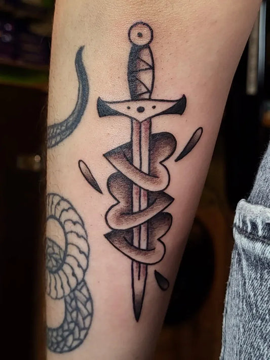 Medium Traditional Dagger and Heart Wrapped in Snake Tattoo on Men Arm by @daan_kessel