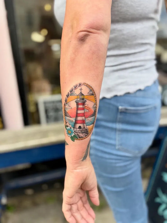 Medium Traditional Lighthouse and Sunset Tattoo on Women Arm by @dani_tattooer