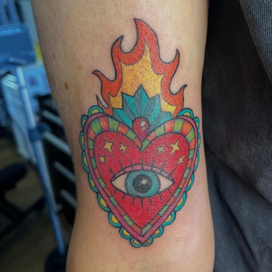 Medium Traditional Sacred Heart with Flames and Eye Tattoo on Women Arm by @silly.goose.tattoo