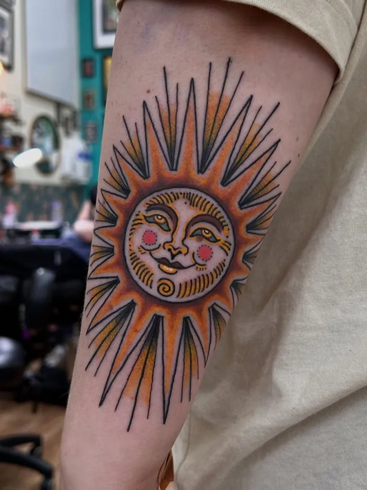Medium Traditional Sun with Face on Women Arm Tattoo by @laurakennedytattoo