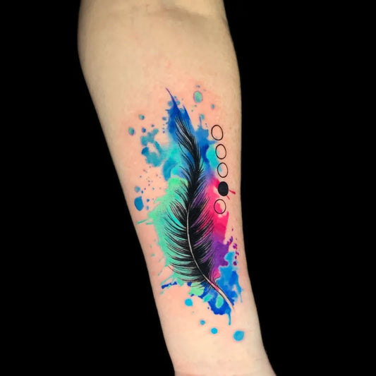 Medium Watercolor Feather with Dots and Splashes Tattoo on Women Arm by @redemptiontattoostudios