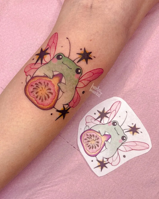 Medium Watercolor Frog with Wings and Pomegranate Tattoo on Women Forearm by @herbabuszka