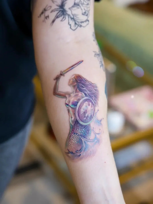 Medium Watercolor Mermaid Warrior Tattoo on Women Arm by @sang.tattoos