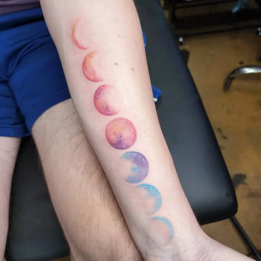 Medium Watercolor Moon Phases Tattoo on Women Arm by @dahlfacetattoos