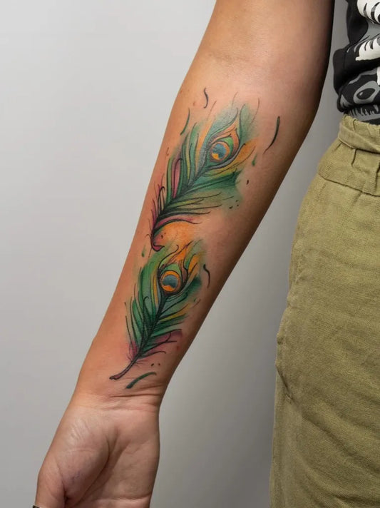 Medium Watercolor Peacock Feathers Tattoo on Women Arm by @inkarmen.tattoos