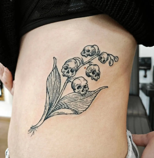 Medium Woodcut Lily of the Valley with Skulls Tattoo on Women Side by @barbara.tattoos