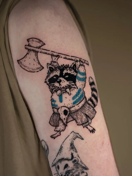 Medium Woodcut Raccoon with Axe and Skirt Tattoo on Men Upper Arm by @forestwitch_bowien