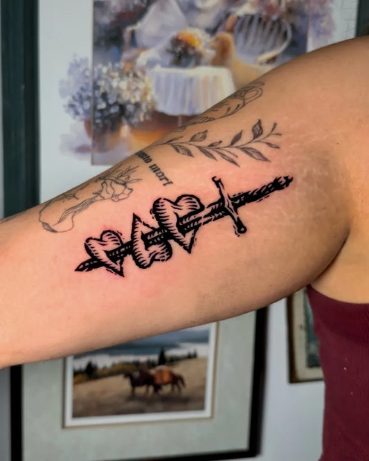 Medium Woodcut Sword with Hearts Tattoo on Women Arm by @kenziecooperart
