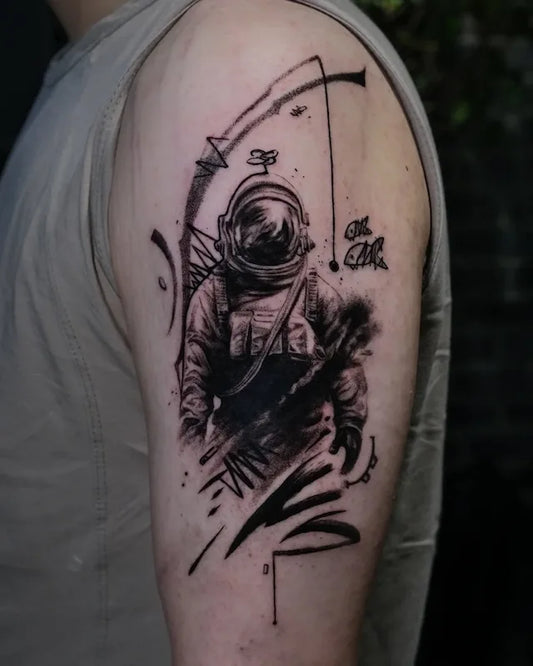black and grey abstract astronaut fishing tattoo on man upper arm