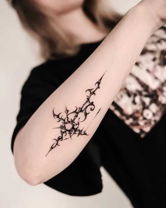 Small Abstract Spiky Cross Tattoo on Women Arm by @auua.tattoo