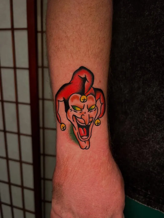 Small American Traditional Jester Mask on Men Wrist Tattoo by @attila_tatts