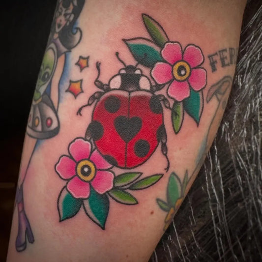 Small American Traditional Ladybug and Flowers Tattoo on Women Arm by @prkrstt2s