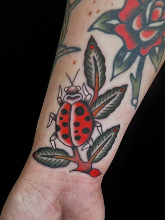 Small American Traditional Ladybug with Rose on Women Arm Tattoo by @penny_tattoos_