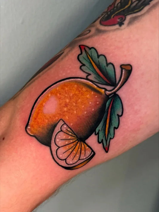 Small American Traditional Lemon Slice with Leaves on Men Arm Tattoo by @castlekeeptattoo
