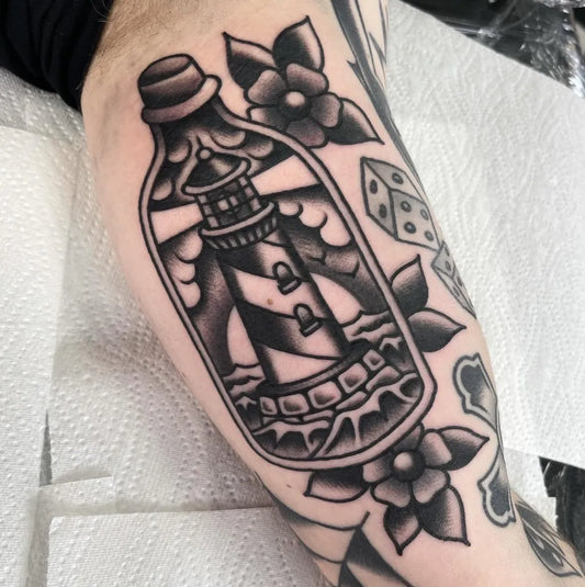 Small American Traditional Lighthouse in Bottle with Dice on Men Arm Tattoo by @tattoos_by_callum