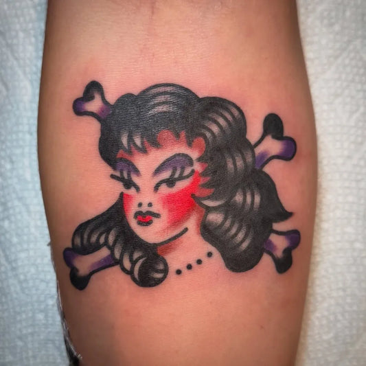 Small American Traditional Pinup with Crossed Bones on Women Arm Tattoo by @eriksheppardtattoo