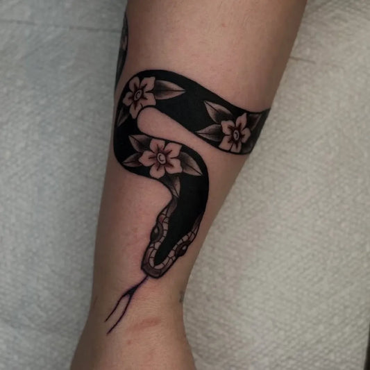 Small American Traditional Snake with Flowers on Women on Arm Tattoo by @jennasze.tattoos