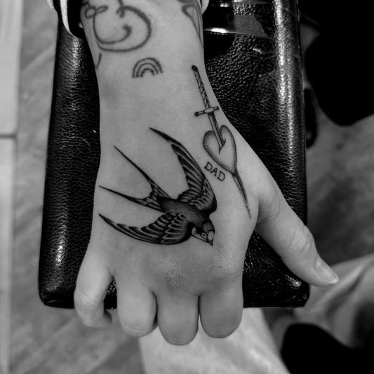 Small American Traditional Swallow Heart Dagger Tattoo on Women Hand by @violatattoos