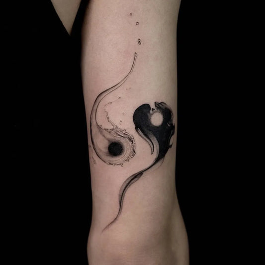 Small Black Ink Watercolor Yin Yang Tattoo on Women Arm by @txttoo
