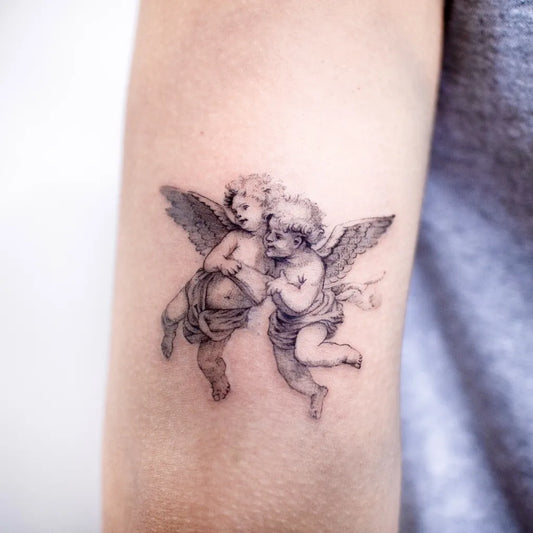 Small Black and Grey Angel Cherubs on Women Arm Tattoo by @arona_tattoo