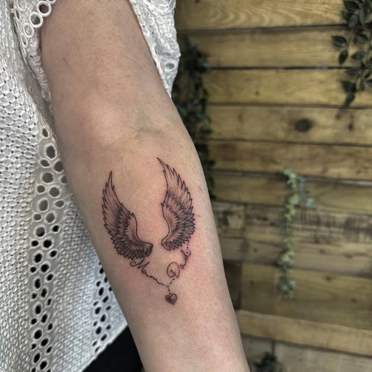 Small Black and Grey Angel Wings Heart Tattoo on Women Arm by @lc_evermore