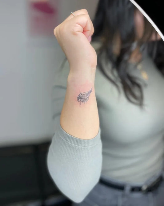 Small Black and Grey Angel Wings Tattoo on Women Wrist by @finelinesby.aj