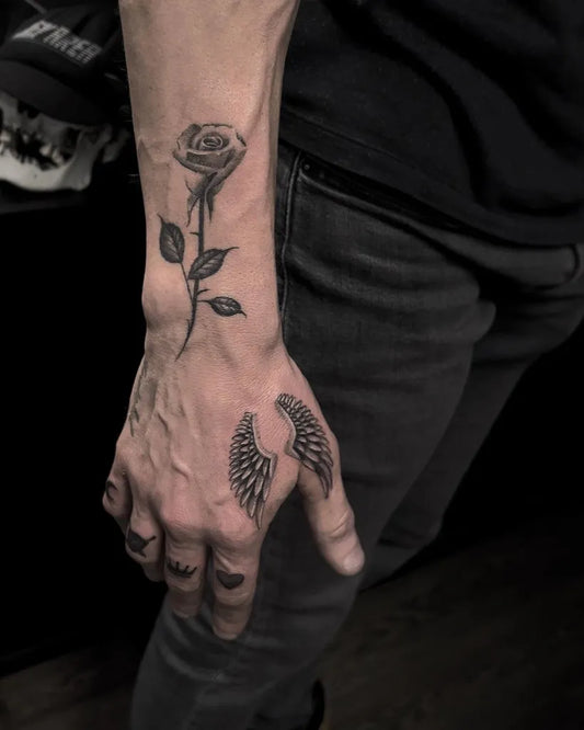 Small Black and Grey Angel Wings and Rose Men Hand by @aroncowlestattoo