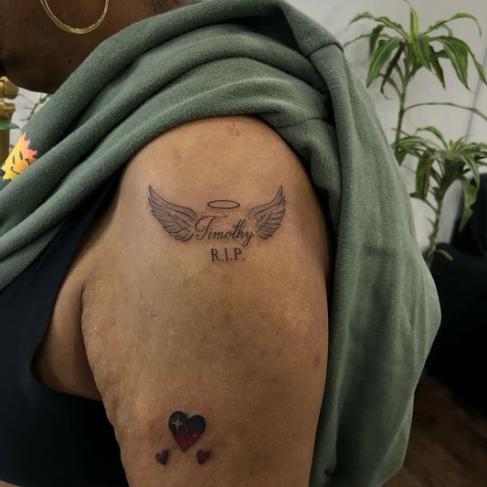 Small Black and Grey Angel Wings with RIP and Hearts Tattoo on Women Shoulder by @inkfusion_tattoo_studio
