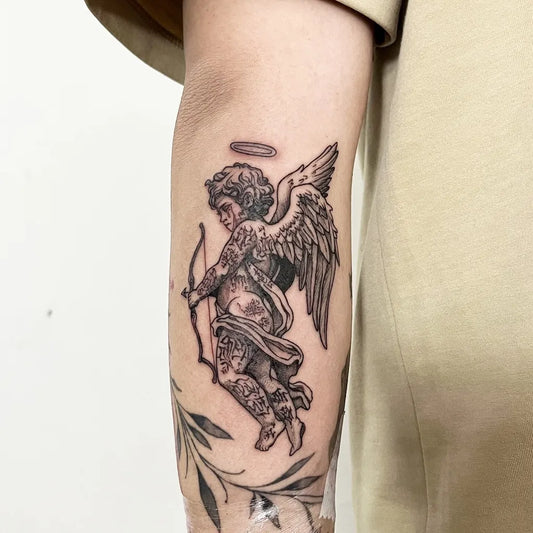 Small Black and Grey Angel with Bow and Leaves on Men Arm Tattoo by @holyinktattoo