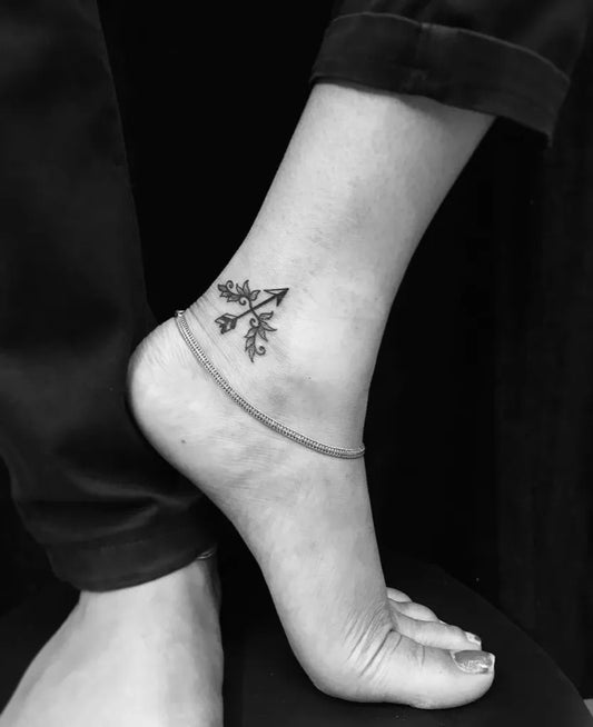 Small Black and Grey Arrow and Flowers Tattoo on Women Ankle by @roy_tattooart