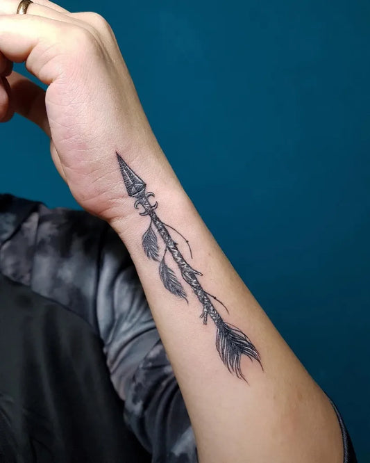 Small Black and Grey Arrow with Feathers Tattoo on Men Wrist by @rize.ink