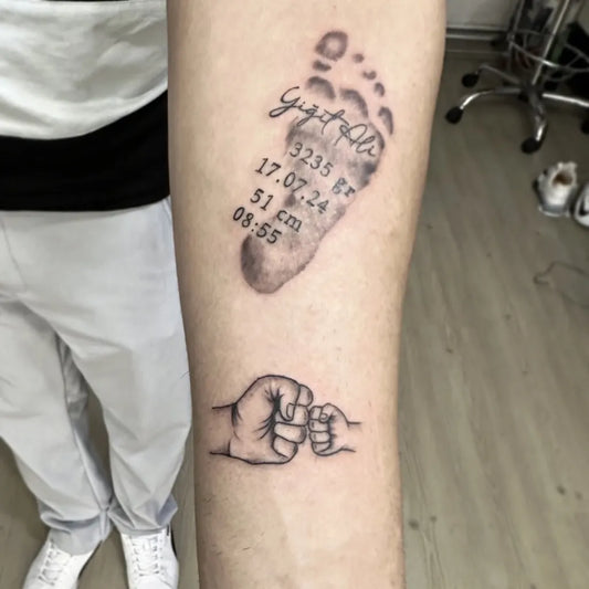 Small Black and Grey Baby Footprint and Fist Bump Family Tattoo on Men Arm by @ahmetgulsentattoo