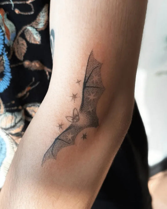 Small Black and Grey Bat and Stars Tattoo on Women Arm by @seraphina.jt