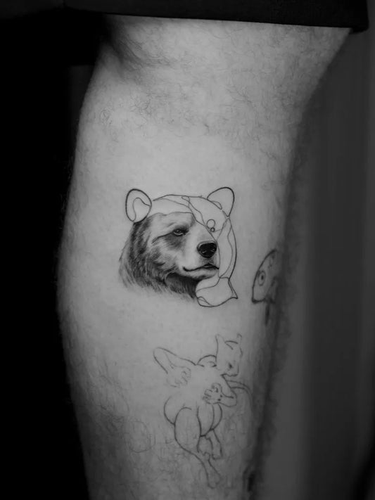 Small Black and Grey Bear and Cherub on Men Leg Tattoo by @phouphou.ink