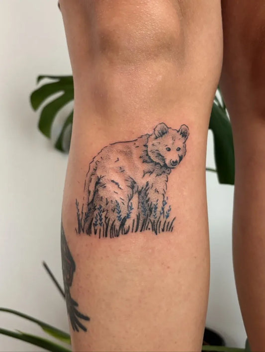 Small Black and Grey Bear with Grass on Women Thigh Tattoo by @ghostkartattoo
