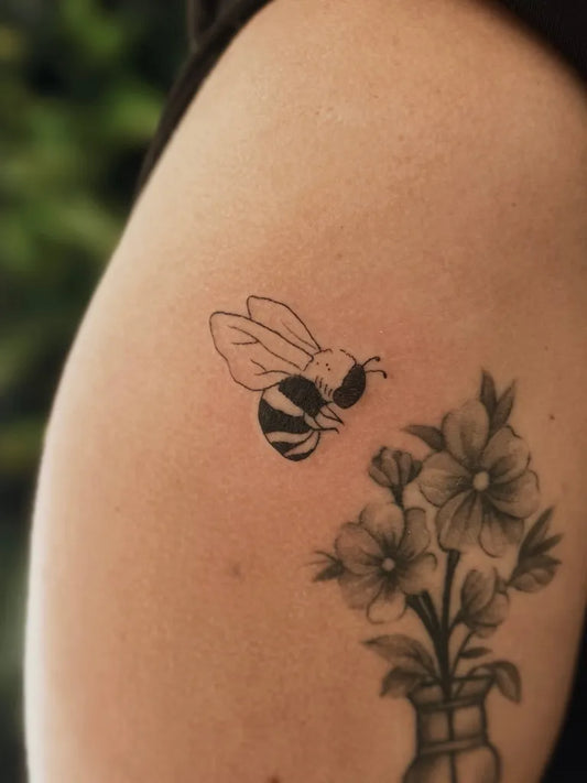 Small Black and Grey Bee and Flowers on Women Arm Tattoo by @saraawt.ink