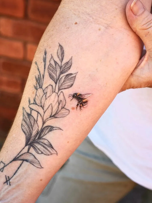 Small Black and Grey Bee and Flowers on Women Arm Tattoo by @tattoo.by_jinnie