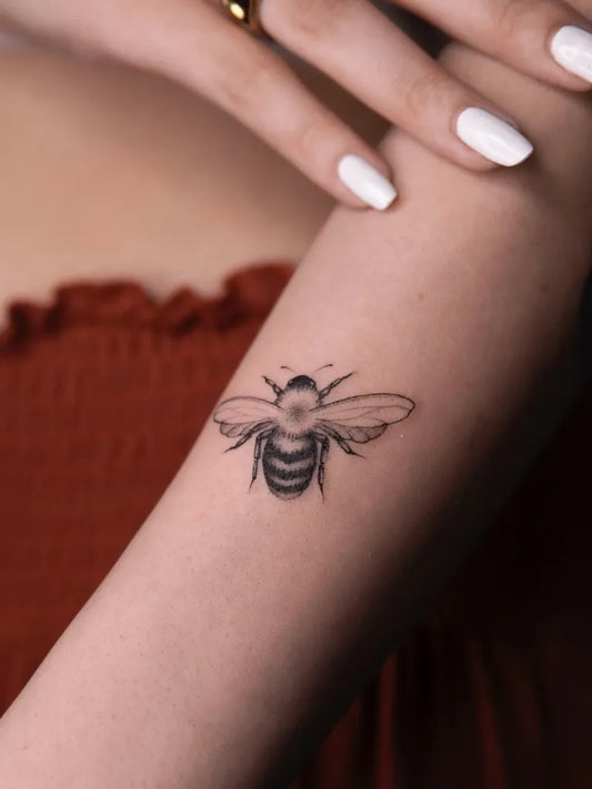 Small Black and Grey Bee on Women Arm Tattoo by @danila_gold_