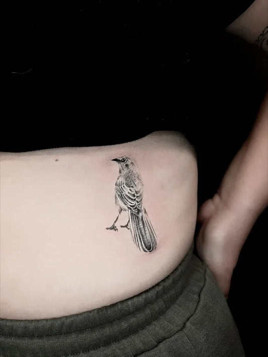 Small Black and Grey Bird Tattoo on Women Hip by @venus.tats