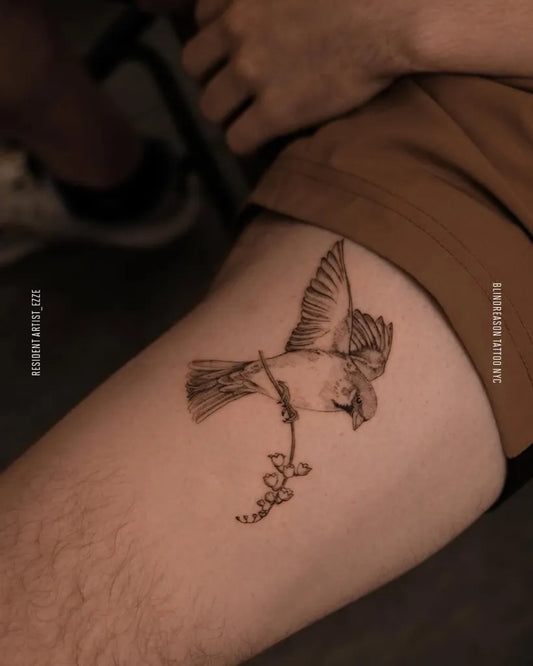 Small Black and Grey Bird with Flower Tattoo on Men Thigh by @blindreasontattoo