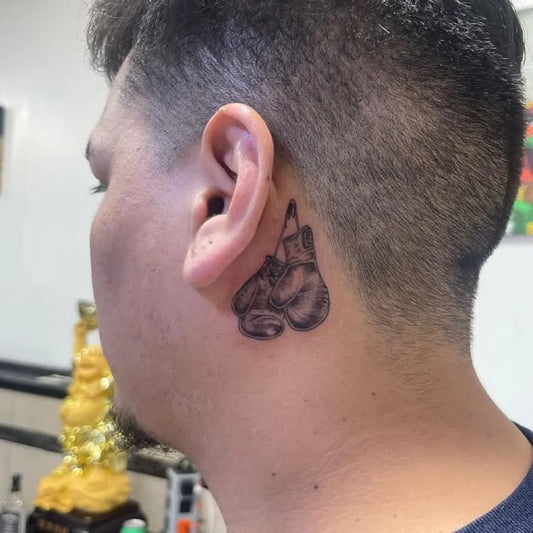 Small Black and Grey Boxing Gloves Tattoo on Men Behind the Ear by @inkfusion_tattoo_studio