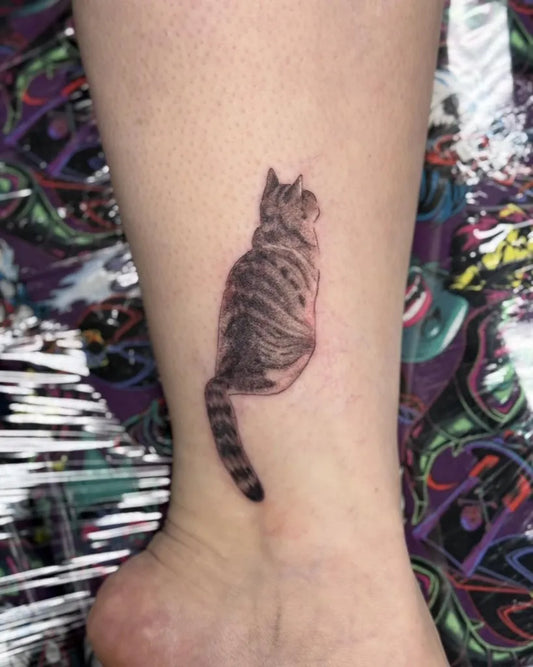 Small Black and Grey Cat Tattoo on Women Ankle by @inflictionstattoos