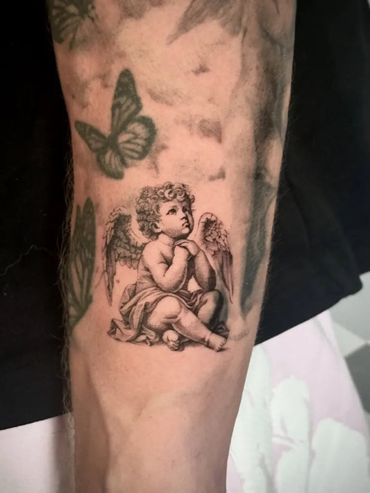 Small Black and Grey Cherub Tattoo on Men Arm by @tattoobycoco