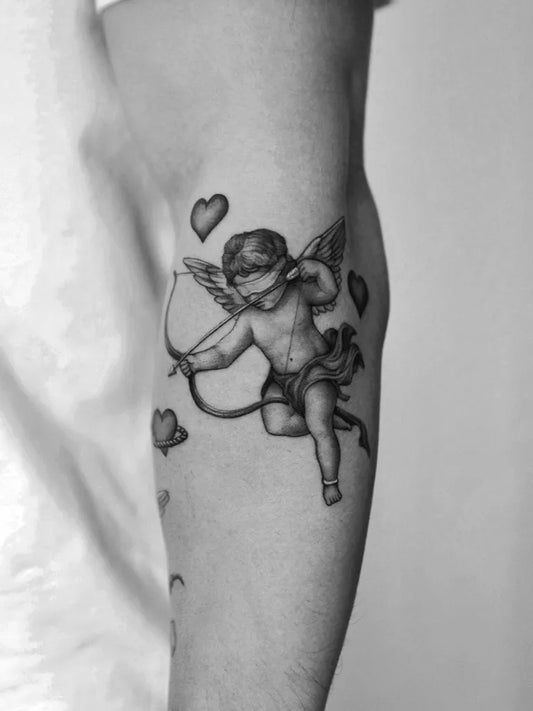 Small Black and Grey Cherub with Arrow and Hearts Tattoo on Men Upper Arm by @quindaytattoos