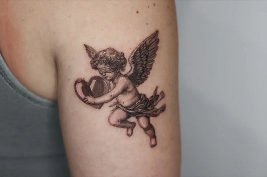 Small Black and Grey Cherub with Heart Tattoo on Women Upper Arm by @kayatatt