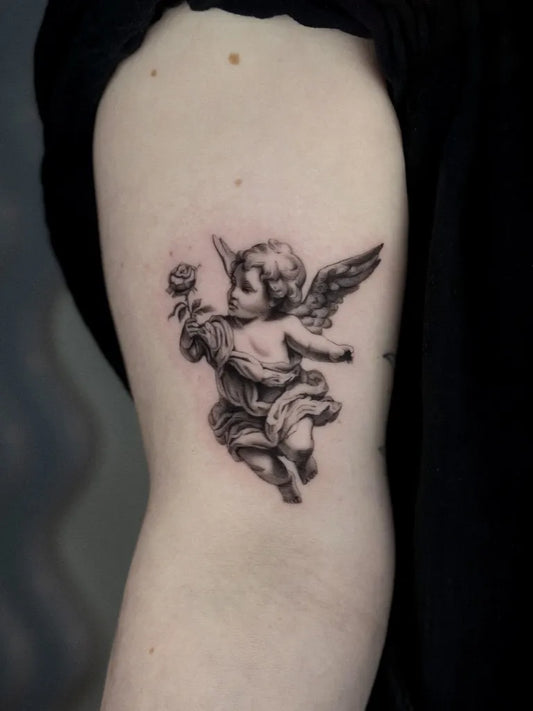 Small Black and Grey Cherub with Rose Tattoo on Women Arm by @rhiannon.ink