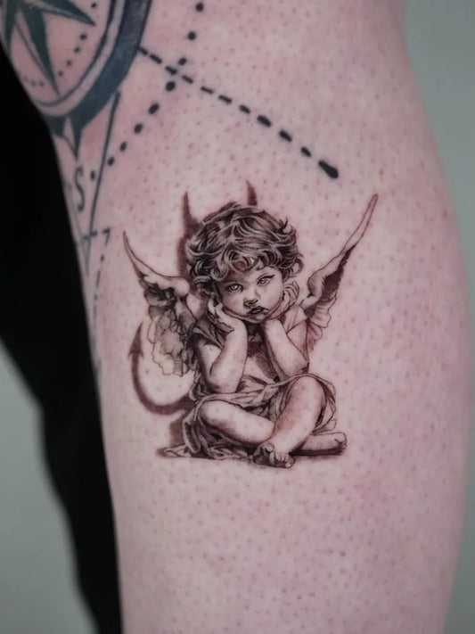 Small Black and Grey Cherub with Wings Tattoo on Women Arm by @saintmichaeltattoo