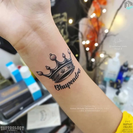 Small Black and Grey Crown Name Tattoo on Men Forearm by @tattoology_studio
